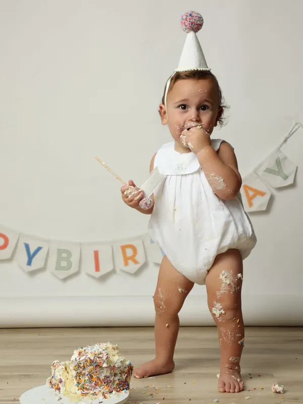Baby in a party hat at a first birthday cake smash, studio photography by Photoholic, Monsey NY